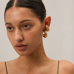 Model wearing Lunaria textured C-hoop earrings with sleek pulled-back hair
