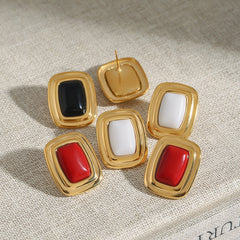 Flat lay of gold rectangular earrings next to architecture sketch