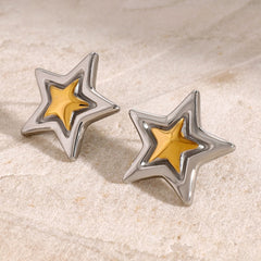 Sculptural star earrings reflecting light on marble background