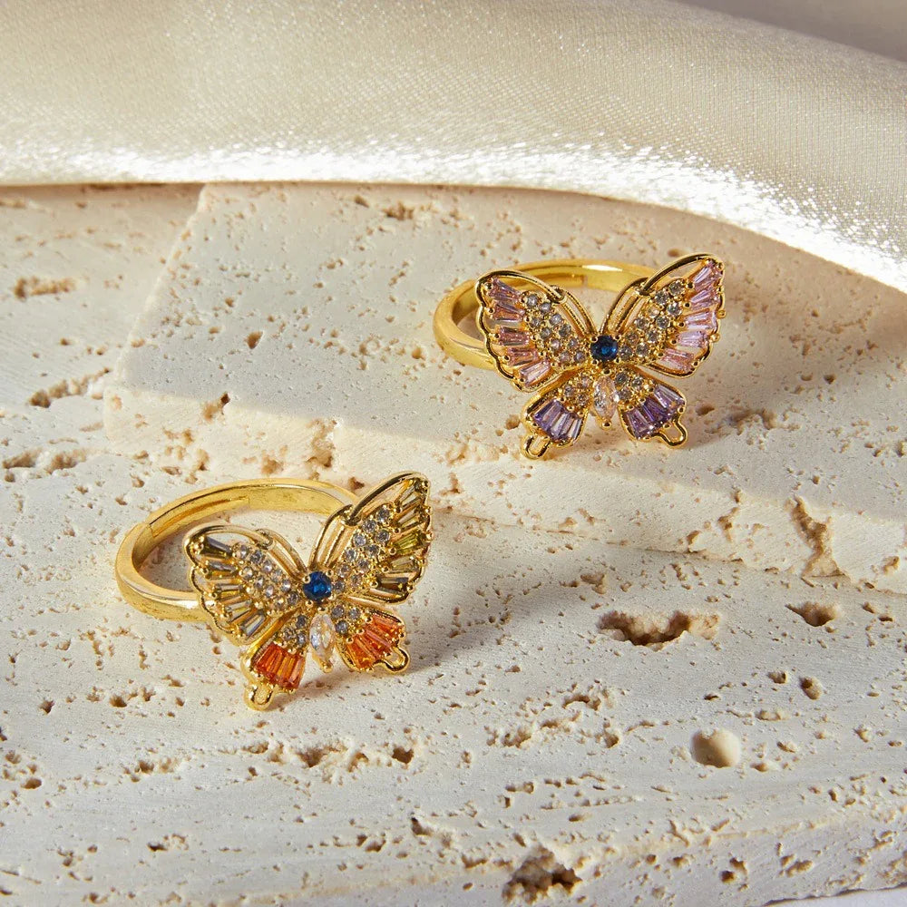 18K gold butterfly-shaped ring with diamond-studded wings on neutral background
