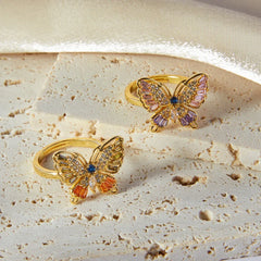18K gold butterfly-shaped ring with diamond-studded wings on neutral background