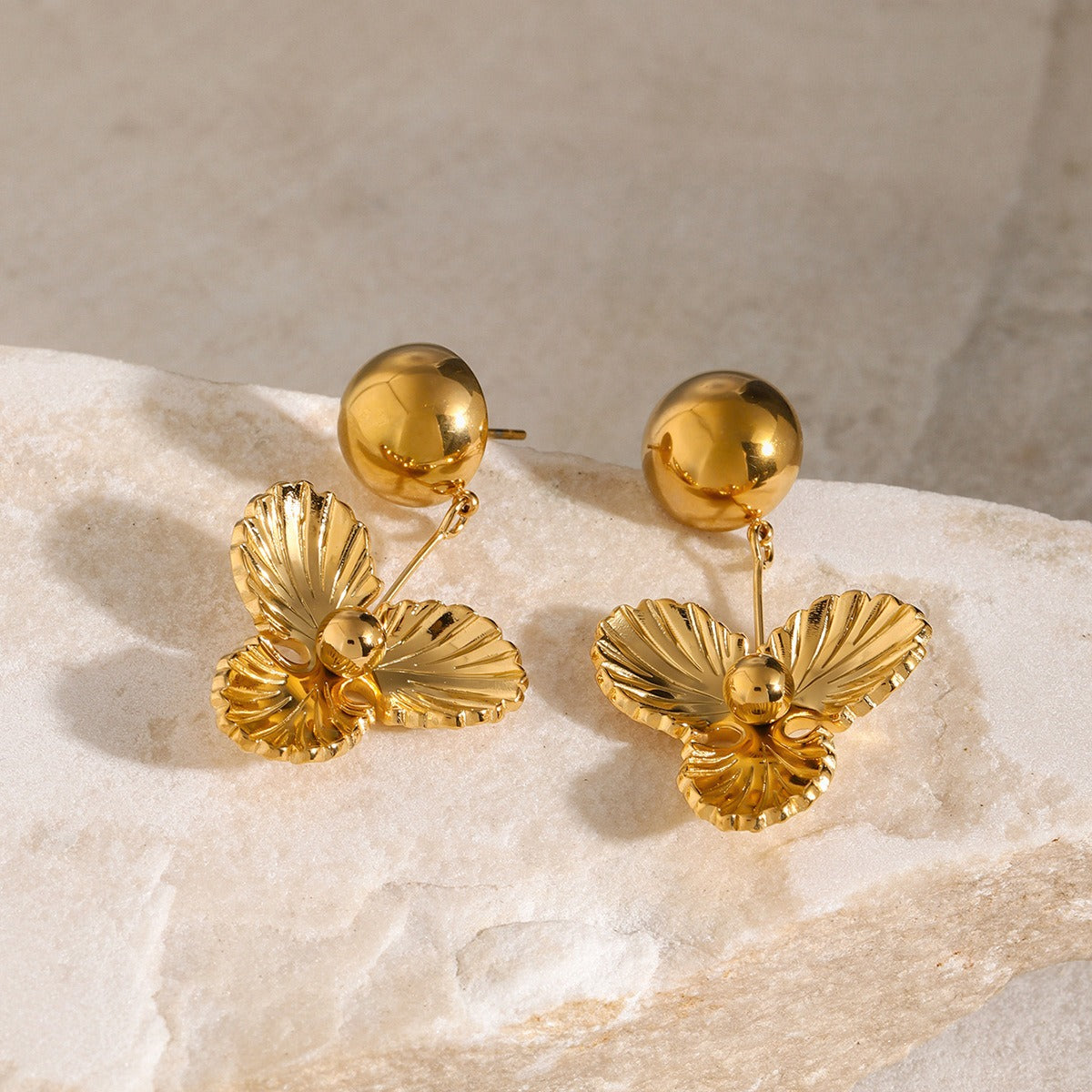 Celene 18K gold dome earrings with three-petal flower detail on white surface
