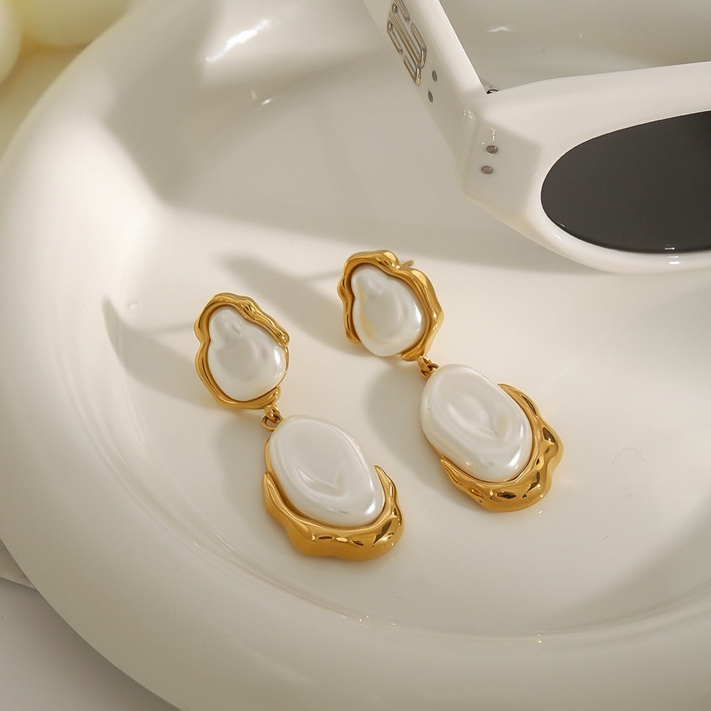 Close-up of irregular pearl earring with 18K gold curved frame