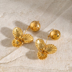 Side view of glossy gold earrings with flower detail reflecting soft light