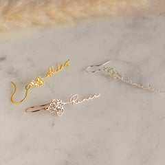 Close-up of silver birthday flower earrings with custom name engraving
