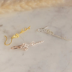 Close-up of silver birthday flower earrings with custom name engraving