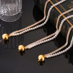 Close-up of 18K gold necklace with square gemstone and pearl detailing