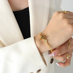 Model wearing airplane-shaped gold bracelet with casual fashion outfit