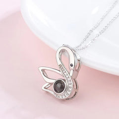Close-up of diamond swan pendant against soft neutral background