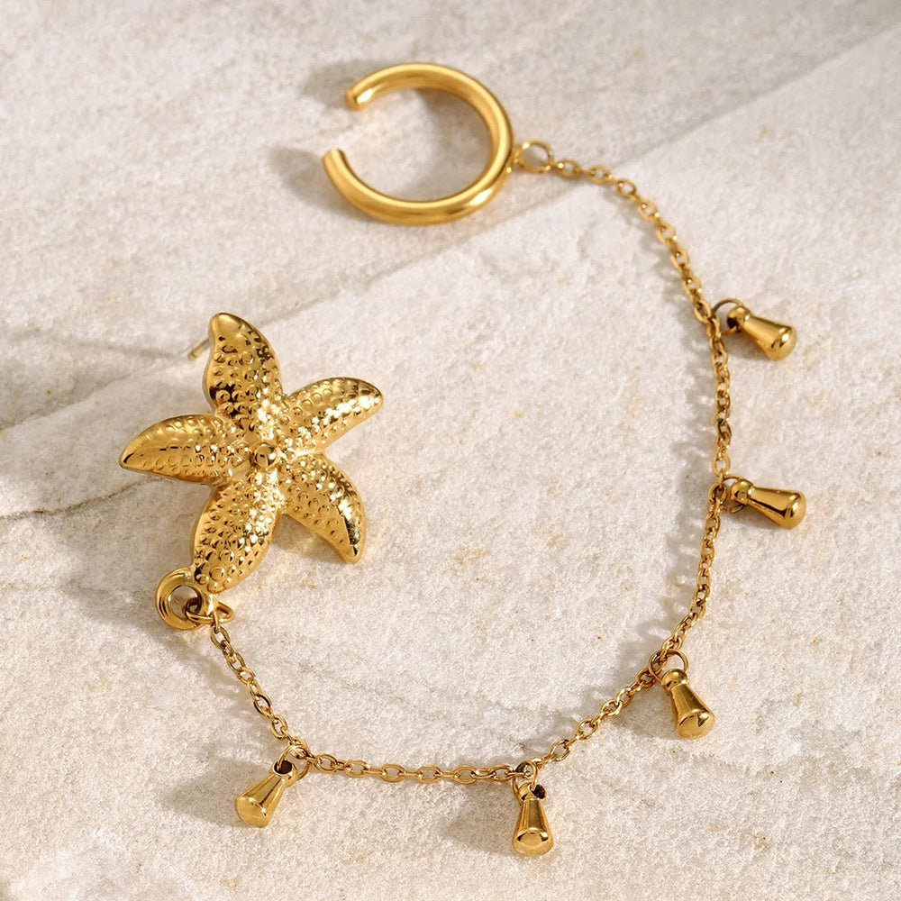 Marina 18K gold starfish earrings styled on seashell background