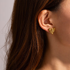 Side view of gold hammered heart earrings on display stand