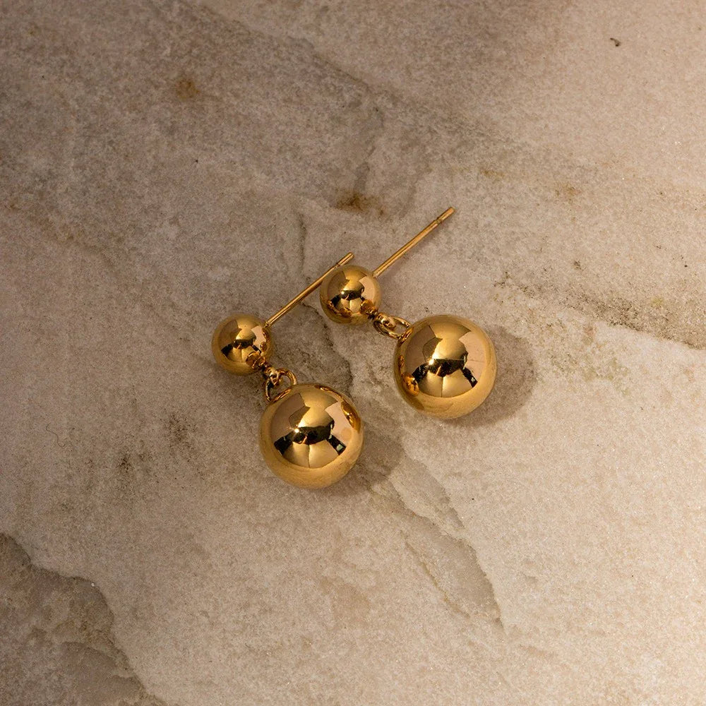 Flat lay of Orla earrings styled with gold chain necklace and rings