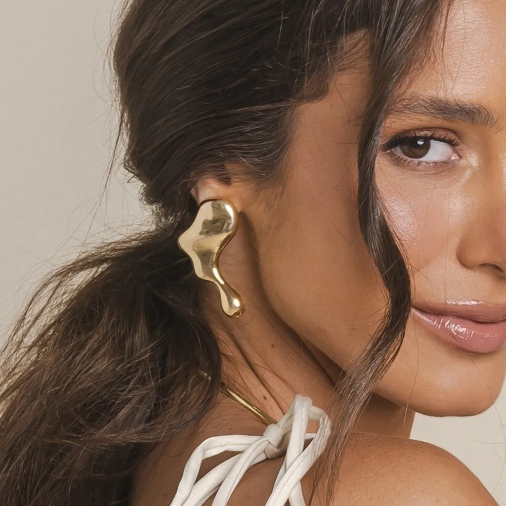 Model wearing bold lava-inspired earrings with black turtleneck