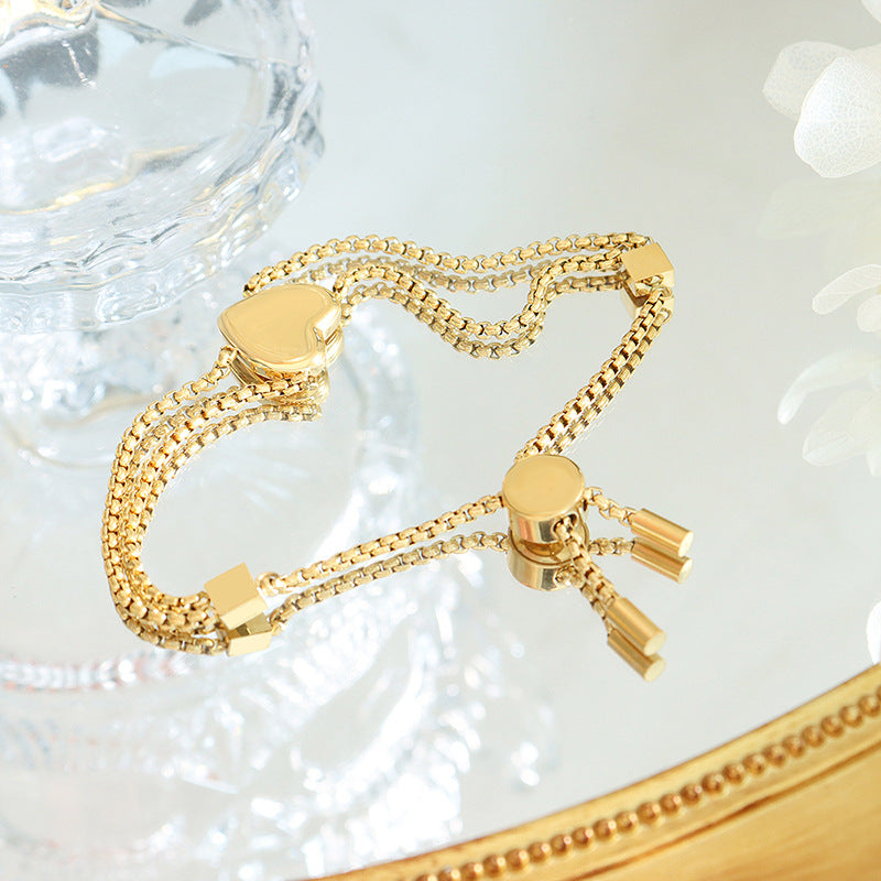 Peach heart charm and geometric square detailing on 18K gold bracelet