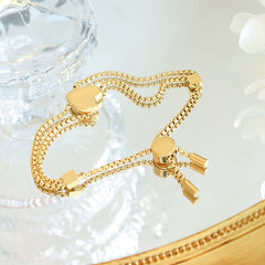 Peach heart charm and geometric square detailing on 18K gold bracelet