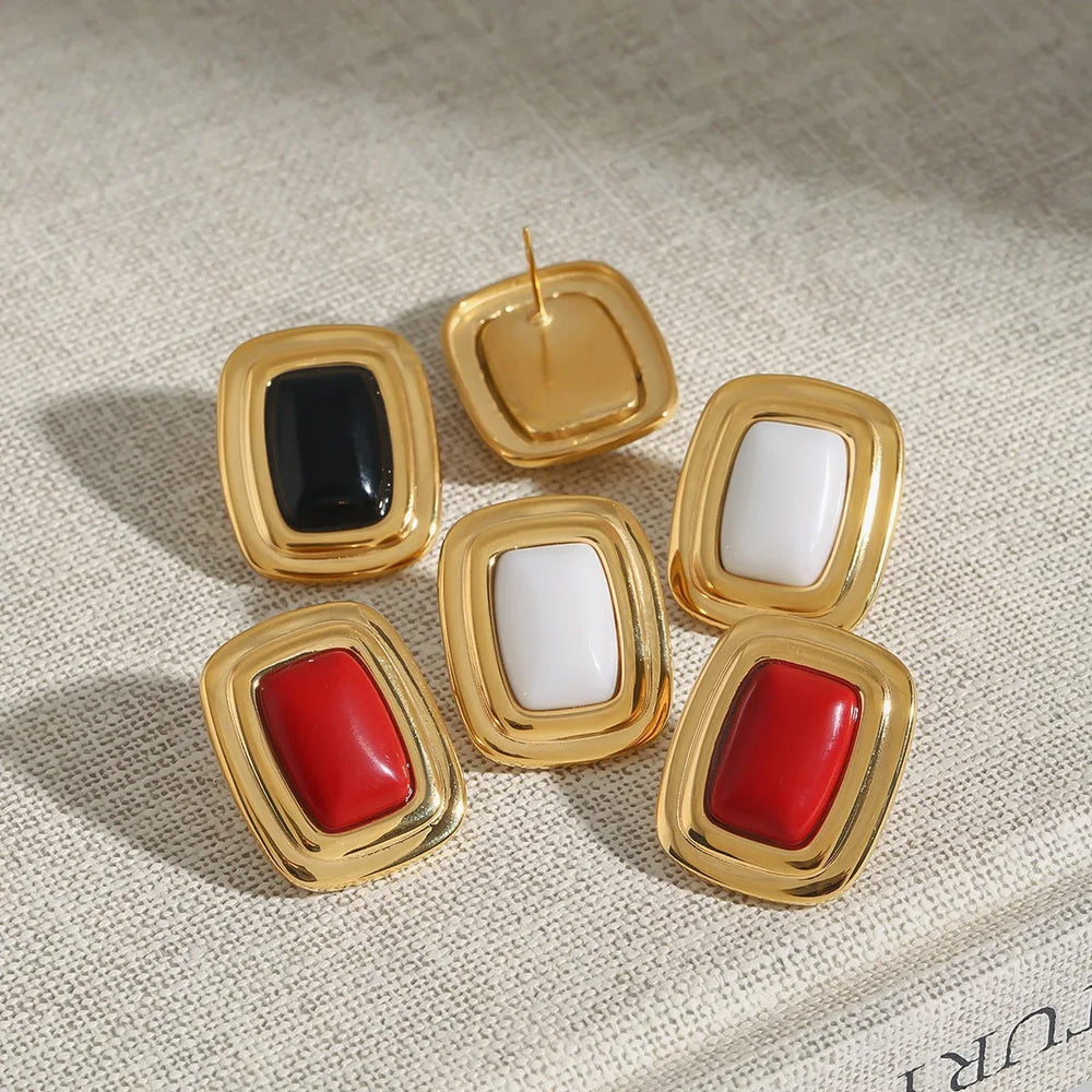 Flat lay of gold rectangular earrings next to architecture sketch
