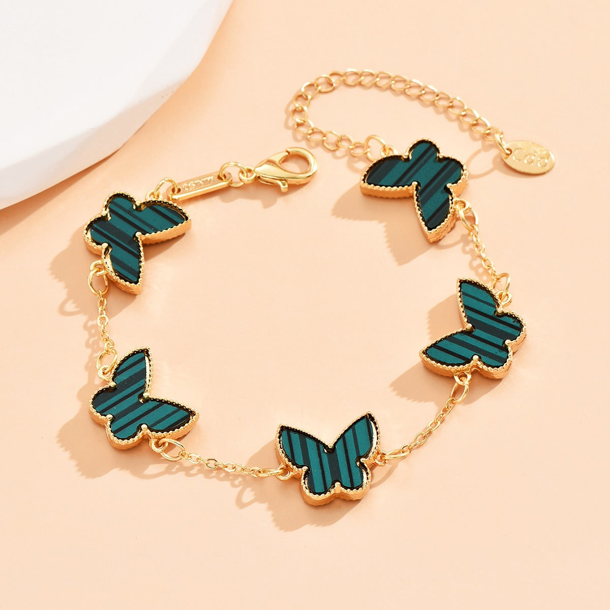 Detailed butterfly charm in 18K gold with mother-of-pearl inlay on bracelet
