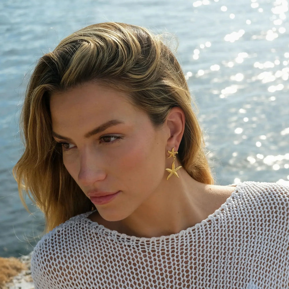 Close-up of ocean-inspired gold earrings with starfish design