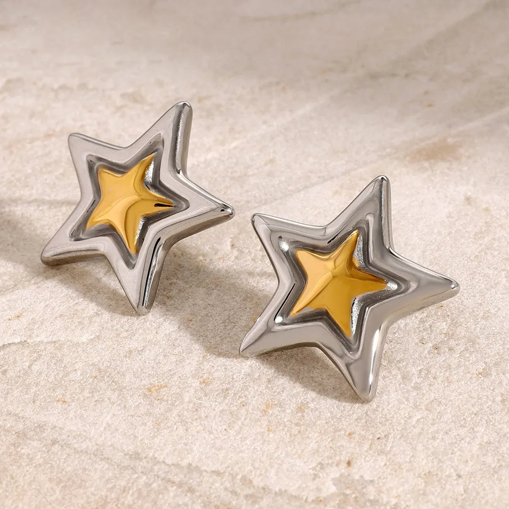 Sculptural star earrings reflecting light on marble background

