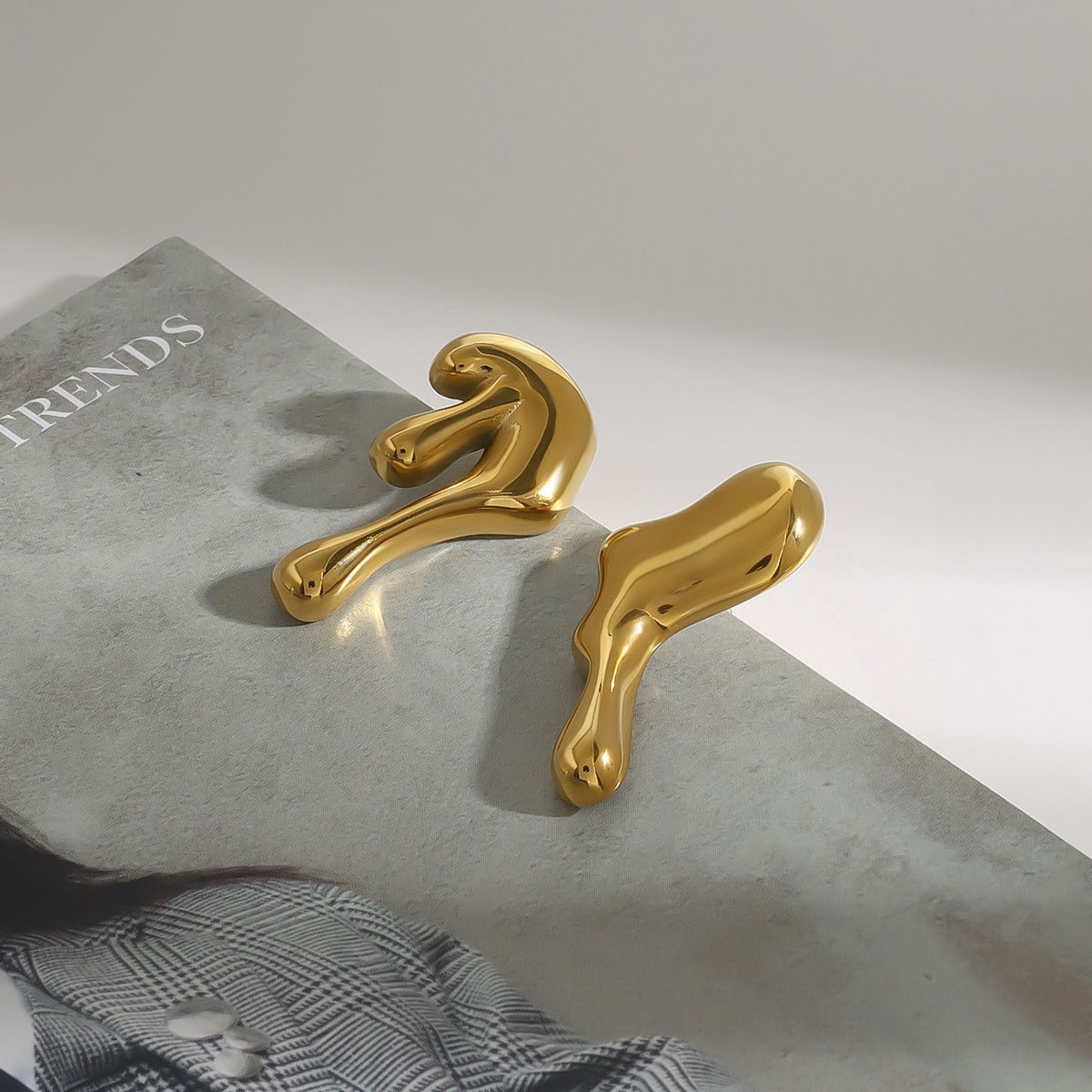 Pair of lava earrings displayed next to molten gold artwork