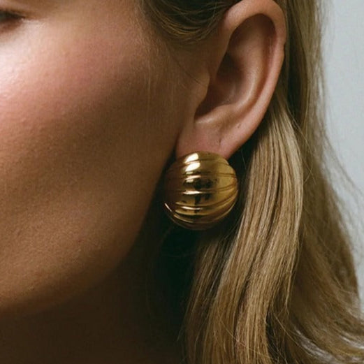 "Detailed view of ribbed texture on gold oval earrings