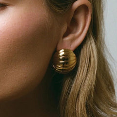 "Detailed view of ribbed texture on gold oval earrings