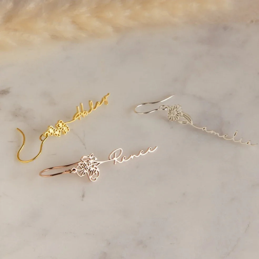Close-up of silver birthday flower earrings with custom name engraving