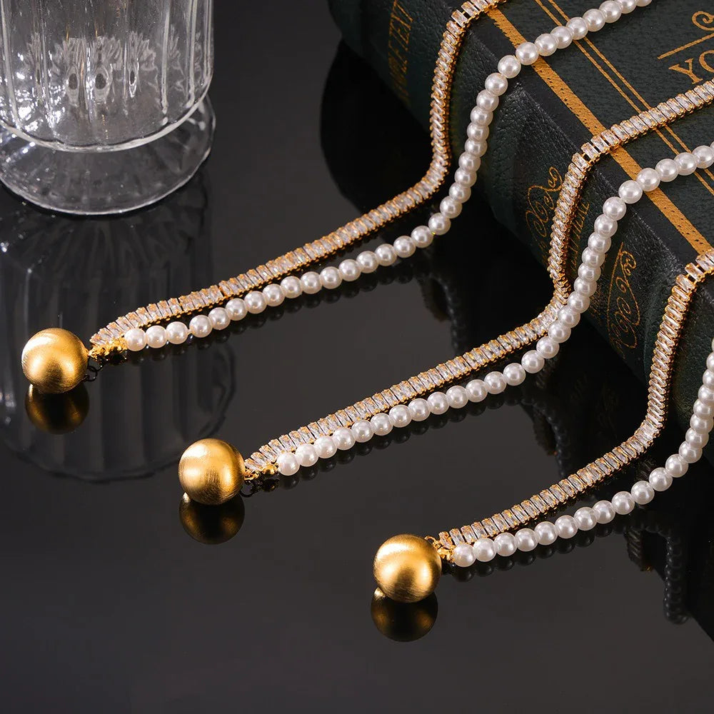 Close-up of 18K gold necklace with square gemstone and pearl detailing