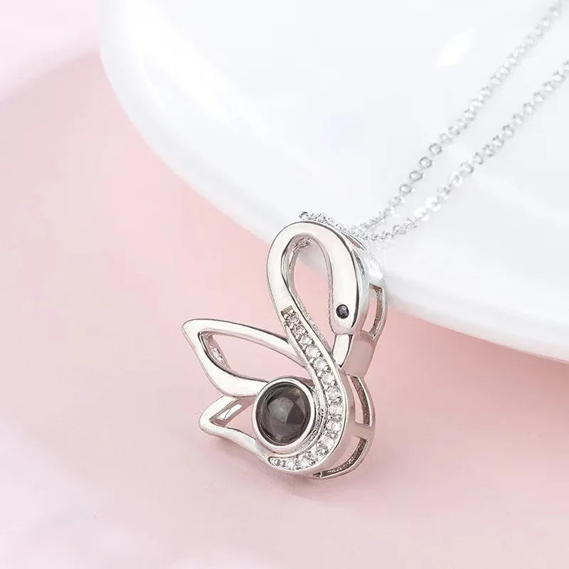 Close-up of diamond swan pendant against soft neutral background