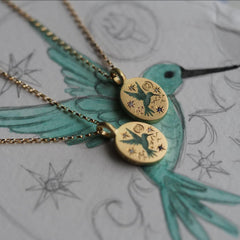 Model wearing patterned gold necklace with artistic pendant