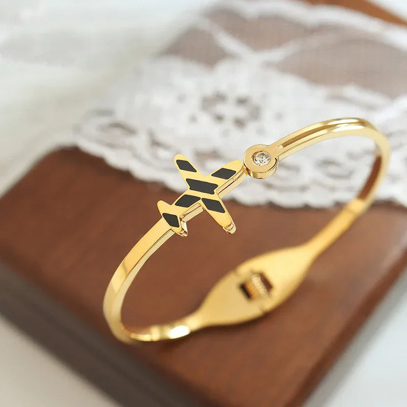 18K gold open bracelet featuring airplane design and gemstone-accented circle